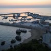 Porto al tramonto con barche ormeggiate e scogli.