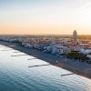 Spiaggia al tramonto con skyline di edifici.
