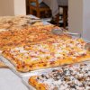Pizze rettangolari assortite su tavoli con posate.