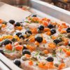 Vassoio di pesce guarnito con olive e pomodori.
