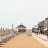 Spiaggia con ombrelloni chiusi e passeggiata.