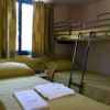 Stanza con un letto singolo e un letto a castello, lenzuola verdi e finestra con tende verdi.
