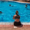 Persona seduta accanto a una piscina con persone che nuotano.