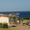 Casa mobile vicino al mare con persone sul vialetto. Cielo sereno e spiaggia in lontananza.