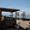 Una persona prende il sole su una sdraio accanto a un patio vicino al mare.