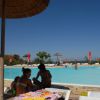 Piscina con persone sedute sotto un ombrellone.
