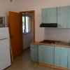 Cucina semplice con frigo, fornelli e armadietti verdi.