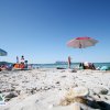 Spiaggia con ombrelloni e persone in riva al mare.