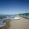 Spiaggia con lettini e ombrelloni blu.