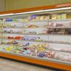 Scaffale refrigerato con vari alimenti e prodotti confezionati esposti ordinatamente.