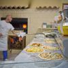Un uomo che prepara pizze davanti a un forno in una pizzeria.
