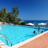 Piscina all'aperto con vista mare e persone che nuotano.