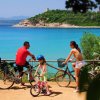Famiglia in bicicletta davanti al mare turchese.