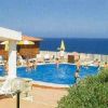Piscina esterna con bambini che nuotano, vista sul mare e ombrelloni gialli.