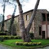 Edificio in pietra con giardino ben curato e grandi alberi.