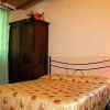 Stanza da letto con letto matrimoniale, armadio scuro, tenda verde e lampada da comodino.