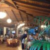 Ristorante illuminato con travi in legno e clienti ai tavoli.