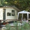 Una casetta prefabbricata con gazebo e fiori davanti.