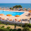 Piscina con lettini e ombrelloni arancioni vicino al mare.