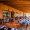 Veranda di un ristorante con tavoli apparecchiati e sedie in legno.