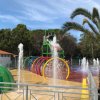 Parco giochi acquatico con spruzzi d'acqua e arco colorato.