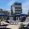 Spiaggia attrezzata con lettini e ombrelloni blu.