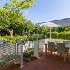 Terrazza con tavolo, sedie e pergolato, circondata da piante verdi.