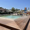 Piscina con bordo in legno vicino a un'area giochi acquatica.