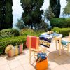 Tavolo su terrazza, alberi e mare sullo sfondo.