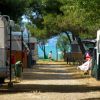 Caravan e tettoie ai lati di un sentiero con vista sul mare.