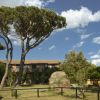 Giardino con alberi e cespugli, edificio in mattoni con un tetto a tegole.