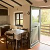 Cucina rustica con tavolo rettangolare e porta aperta su balcone.