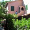Esterno di una casa rosa con persiane verdi e persona su scala.