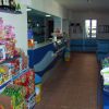 Un negozio con scaffali di snack e giocattoli colorati a sinistra, e un bancone blu sulla destra.