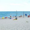 Spiaggia sabbiosa con bagnanti e ombrelloni colorati.