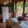 Veranda rustica con tavolo e frigorifero, vista giardino.