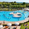 Una piscina affollata circondata da prati e lettini.