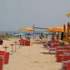 Spiaggia con sedie e ombrelloni giallo-arancio, persone in lontananza.