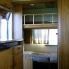Letto a castello in una roulotte con mobile cucina a sinistra.