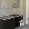 Una cucina moderna con mobili bicolore, fornelli, lavello e sedie di metallo.
