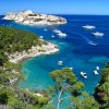 Vista panoramica su una baia con barche e vegetazione rigogliosa.