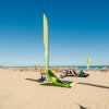 Spiaggia sabbiosa con vele e sdraio.