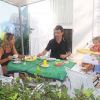 Una famiglia di quattro persone fa colazione su una terrazza, seduti attorno a un tavolo con cibo.