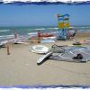 Spiaggia con attrezzature da windsurf e torretta colorata.