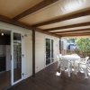 Veranda in legno con tavolo e sedie bianche.