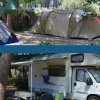 Campeggio con una tenda e un camper sotto gli alberi.
