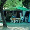 Camper all'ombra con tavolo e sedie all'aperto.
