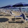 Lettini e ombrelloni blu su una spiaggia sabbiosa sotto un cielo sereno.