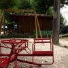 Area gioco con altalene e giochi a molla in un parco.