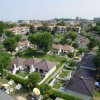 Vista aerea di villette con giardini e ombrelloni.